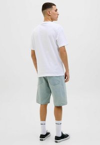 Hvid bomulds t-shirt parret med lyseblå denim shorts. Sorte sneakers med hvide såler og mærkebaserede hvide sokker. Simpelt, afslappet look.