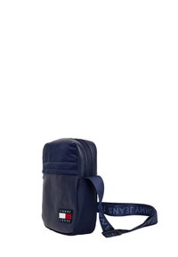 Bolso bandolera rectangular azul marino hecho de material sintético con cierre de cremallera, que presenta un parche con el logo y una correa ajustable con un diseño estampado.