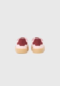 Sneaker rosa con accenti in suede bordeaux, forma arrotondata, suola in gomma e collo imbottito. Dettagli testurizzati sul retro.