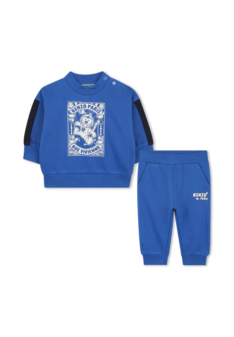 Blauwe tweedelige outfit met een langetermijn top met een grafische print en zwarte schouderaccenten, gecombineerd met bijpassende instapbroeken.