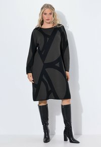 Abito lavorato a maglia a maniche lunghe di colore grigio scuro con un design astratto nero. Caratterizzato da un collo rotondo e una vestibilità comoda, abbinato a stivali neri al ginocchio.