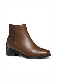 Botas de tobillo de cuero marrón con un acabado suave, paneles laterales elásticos, un tacón bajo y un sutil acento metálico del logo en el lado exterior.