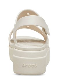 White platform sandals with two adjustable strap design, textured footbed, and the word "crocs" embossed on the heel. Smooth material finish.