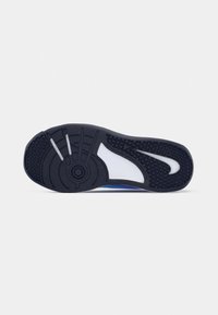 Suela de zapato deportivo azul con una superficie de goma negra texturizada, una sección central blanca y patrones de banda de rodadura distintos para mayor agarre.