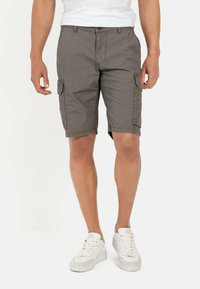 Grå cargo shorts lavet af letvægtsstof, med sidelommer, knaplukning og en afslappet pasform. Stylet med hvide sneakers.
