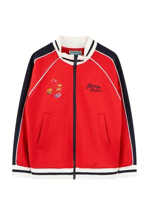 Veste zippée rouge avec accents marine, col et poignets côtelés, détails brodés, et deux poches avant. Présente un passepoil blanc le long des coutures.