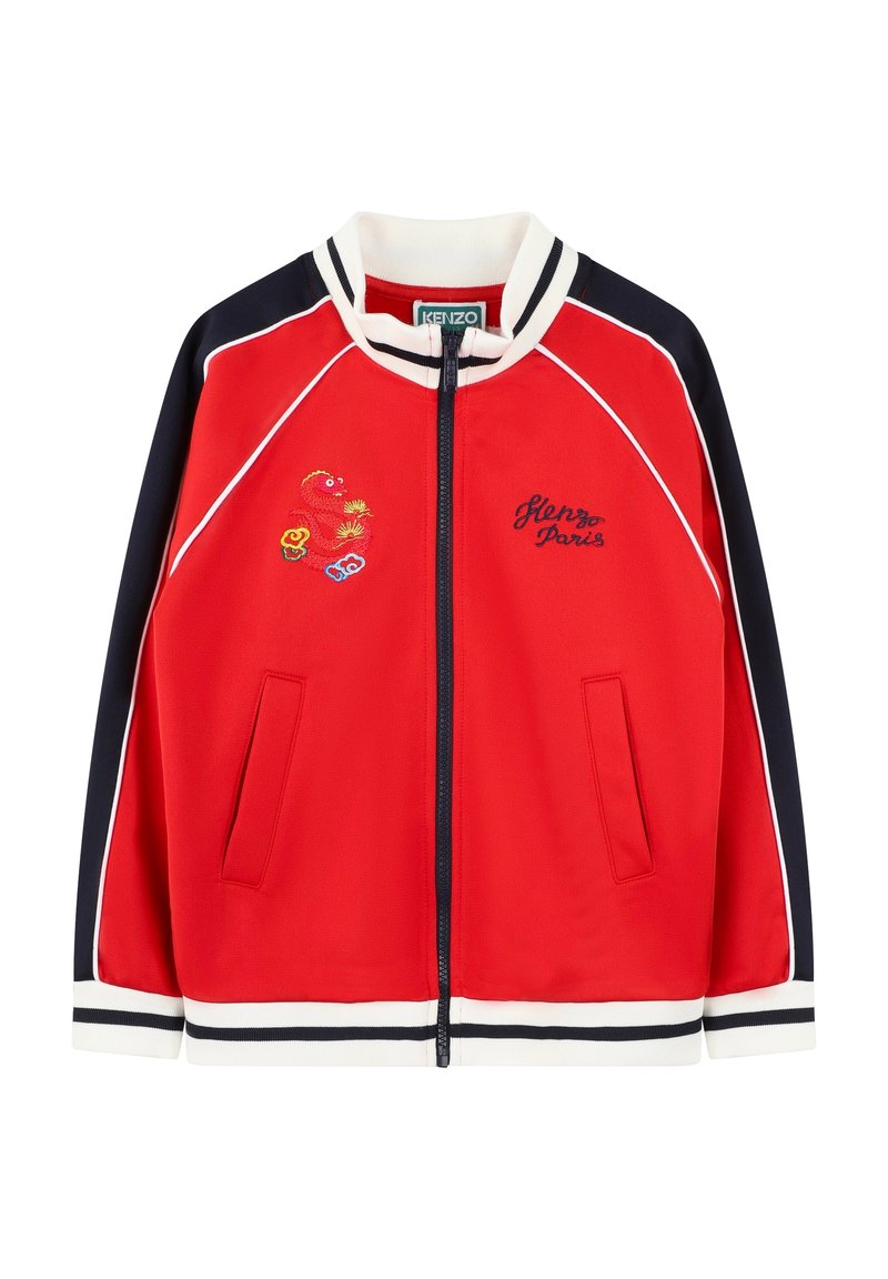 Veste zippée rouge avec accents marine, col et poignets côtelés, détails brodés, et deux poches avant. Présente un passepoil blanc le long des coutures.