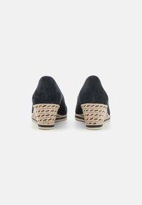 Zeppe nere in suede con dettagli in paglia intrecciata, caratterizzate da una punta affusolata e un design del tacco testurizzato. Finitura liscia, base neutra.