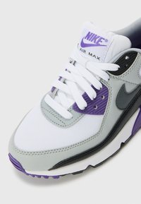 Sivi i bijeli Nike Air Max tenisice imaju ljubičaste detalje, materijale od mrežice i kože, vezice te vidljivo Air jastučenje u potplatu.