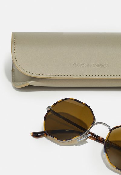 Giorgio Armani solglasögon i oktagonal form med bruna linser. Skalmar i sköldpadds-mönster och silverdetaljer. Inklusive ett beige, texturerat fodral.