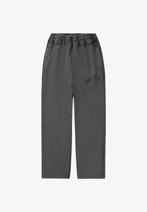 Grijze joggingbroek met een elastische tailleband, twee zijzakken en de tekst "UNITY" in het zwart gedrukt op de linker dij.