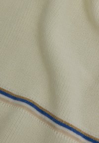 Tissu en tricot beige clair présentant une surface texturée. Il possède des rayures horizontales en fil bleu, rose et doré le long du bord inférieur.