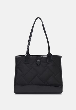 Sort quiltet tote taske med to lange håndtag, blank kant forneden og et lille dekorativt emblem i midten.