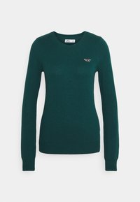 Mörkgrön långärmad tröja med rund halsringning och ribbade ärmslut och nederkant, med en liten röd broderad måslogotyp på vänster bröst.