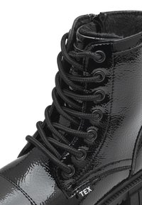 Stivale alla caviglia in pelle verniciata nera con finitura testurizzata, punta tonda, lacci neri, occhielli metallici e interno morbido. Presenta il logo sul lato.