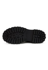 Semelle de botte en caoutchouc noir avec des motifs de crampons profonds et larges, comprenant des formes rectangulaires et triangulaires pour une meilleure adhérence.