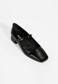 Chaussure Mary Jane noire en cuir verni avec un bout carré, un petit talon carré et une sangle réglable sur le cou-de-pied. Motif crocodile texturé.