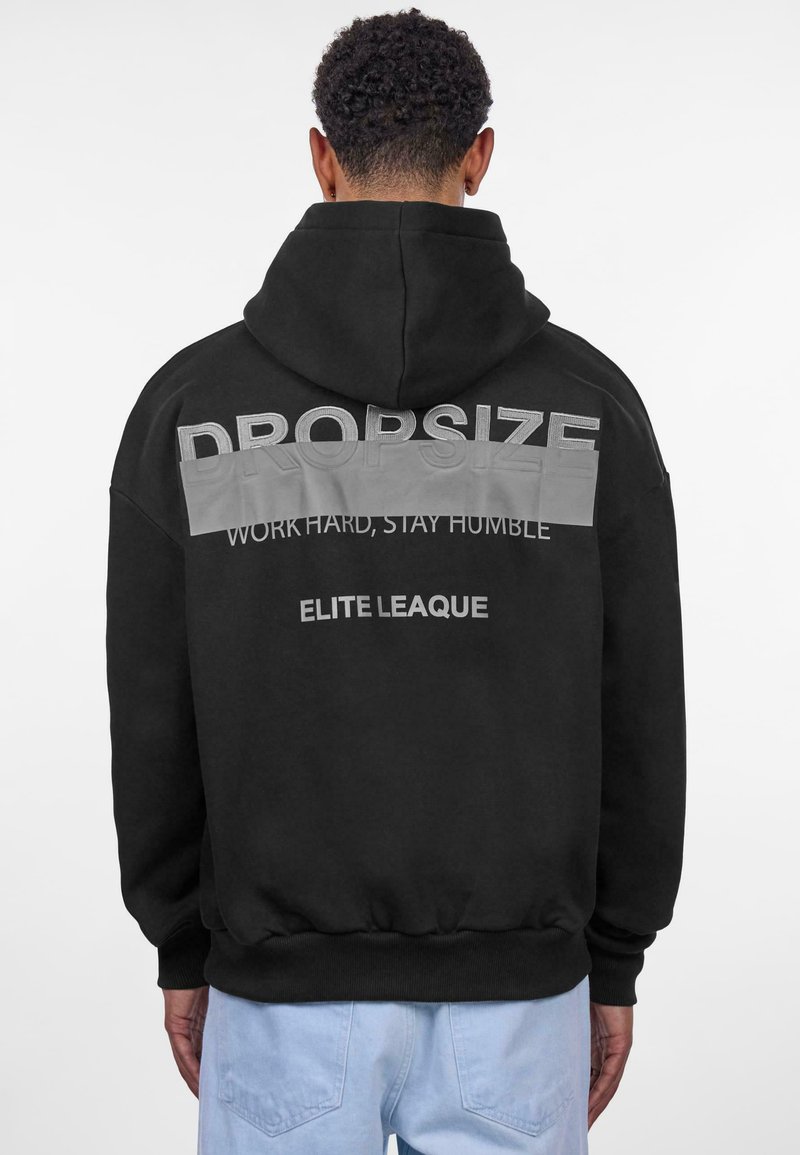 Haut à capuche noir avec une capuche, des poignets côtelés et un ourlet. Le texte au dos comprend "DROPSIZE" en lettres capitales, avec "WORK HARD, STAY HUMBLE" et "ELITE LEAGUE."