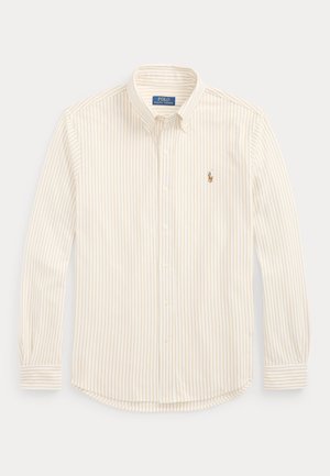 Chemise à manches longues boutonnée, rayures verticales beige et blanches, avec logo Polo Ralph Lauren brodé sur la poitrine gauche.