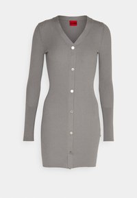 Grijze ribben cardigan met een V-hals, lange mouwen en zilveren knoopsluiting aan de voorkant. Heeft zijsplitten aan de onderkant.