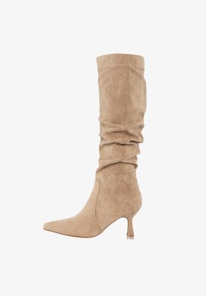 Stivale beige in camoscio fino al ginocchio con punta appuntita, gambale morbido e piccolo tacco a spillo.