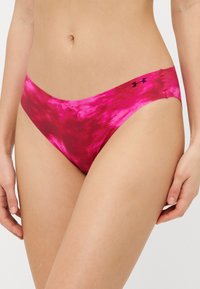 Rózsaszín batikolt bikini alsó sima, rugalmas textúrával. Keskeny oldalai vannak, és az egyik oldalon egy kis fekete logó díszítés található.