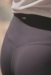 Mustad mustad, mis on valmistatud venivast kangast. Omab kõrget vöökohta, millel on "self." logo, sile struktuur ja lamendatud saumaid mugavuse tagamiseks.