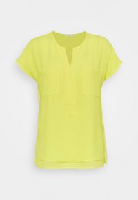 Top a maniche corte di un vivace giallo con scollo a V, due tasche sul petto e orlo arrotondato. Realizzato in un tessuto leggero e semi-trasparente.