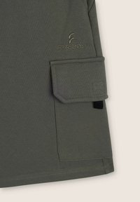 Sudadera de manga larga verde oliva hecha de una tela suave y elástica. Cuenta con un bolsillo de parche en la manga y un logotipo bordado en un color a juego.