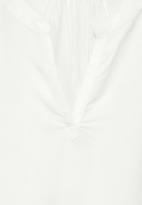 Blusa bianca con scollatura a V, tessuto morbido, leggermente arricciata all'ordine del collo e un piccolo bottone decorativo al centro.