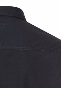 Navy shirt with a structured collar, featuring a smooth texture and subtle stitching details. Branding visible on the collar area.