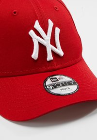 Boné de basebol vermelho com logotipo branco bordado, viseira firme e faixa ajustável. O material parece ser algodão com uma textura suave.