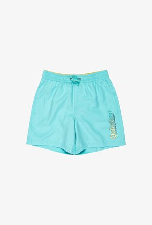 Niño con pantalones cortos de baño sueltos de color azul claro con cintura de cordón y pequeño gráfico en la pierna derecha, de pie descalzo contra un fondo blanco.