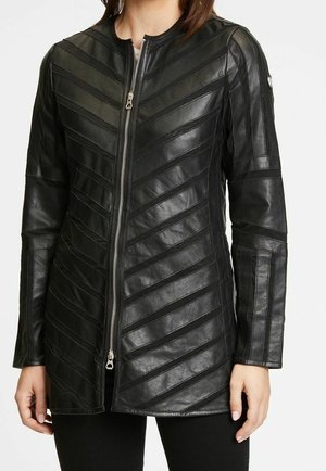 Veste en cuir noir avec des panneaux cousus en diagonale, une fermeture éclair à l'avant et des manches longues portée par une personne.