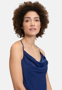 Camisole en satin bleu marine avec un décolleté en cowl, des bretelles fines et une silhouette fluide. Texture douce avec des détails drapés à l'avant.
