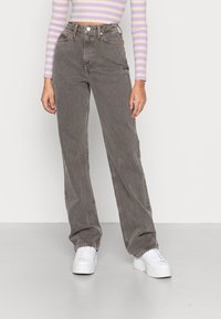 Grey wide-leg jeans made of denim, featuring a high waist, front pockets, and light stitching. Paired with white platform sneakers.