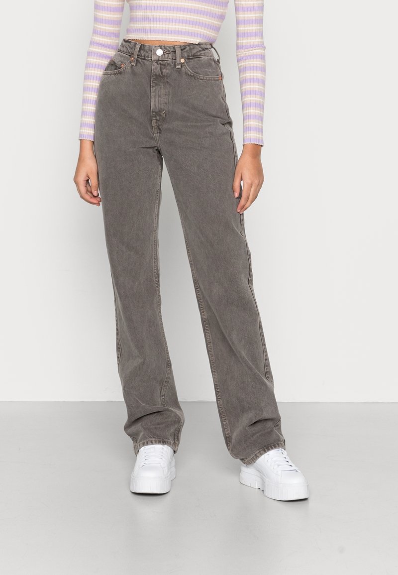 Grey wide-leg jeans made of denim, featuring a high waist, front pockets, and light stitching. Paired with white platform sneakers.