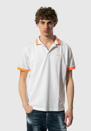 Maglietta polo bianca con accenti arancioni sul colletto e sulle maniche, con un piccolo logo sul petto. Tessuto morbido e vestibilità classica.