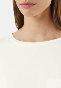 Witte T-shirt met een ronde halslijn en een klein zakdetail, gemaakt van gladde stof, met een minimalistisch en schoon ontwerp.