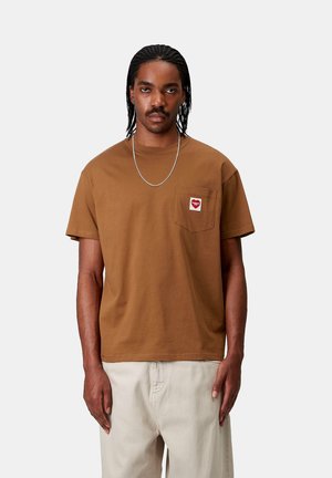 Camiseta de algodón marrón con un bolsillo en el pecho que presenta un diseño de corazón rojo. Cuello redondo y mangas cortas. Textura suave y ajuste relajado.