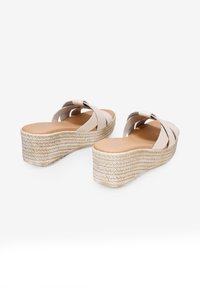 Sandalias de cuña en suave cuero beige con correas entrecruzadas y una base de yute tejido texturizado, con puntera redonda y plantilla acolchada.