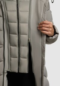 Hellgraue Daunenjacke mit einem Reißverschluss an der Vorderseite und einem gesteppten Innenfutter. Der Stoff wirkt glatt mit einem glänzenden Finish.