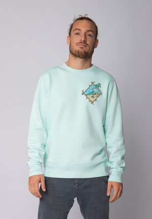 Licht mintgroene sweatshirt met ronde hals, ribgebreide manchetten en een diamantvormige illustratie van palmboom en golven op de borst.