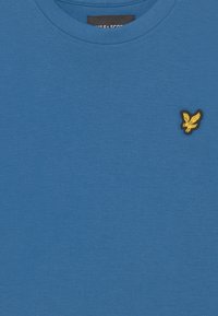 Blauw T-shirt van katoen, met een ronde halslijn en een klein geborduurd geel logo van een vogel op de linkerkant van de borst.