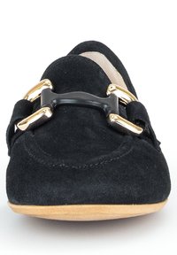 Schwarze Wildleder Slipper haben eine runde Spitze und eine dekorative goldene und schwarze Schnalle auf der Vorderseite, mit einer hellen Gummisohle.