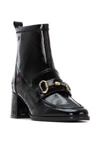 Botín de tobillo de charol negro con tacón grueso, que presenta una correa decorativa y detalles en tono dorado. Textura suave y acabado brillante.