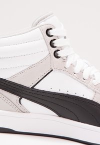 Hochschnitt-Sneaker mit einem weißen Lederobermaterial, grauen und schwarzen Wildlederakzenten, runden Schnürsenkeln und einem gepolsterten Kragen.