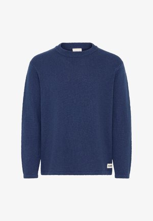 Donkerblauwe gebreide trui met lange mouwen, ronde hals en een klein wit stoffen label bij de onderzoom aan de rechterkant.