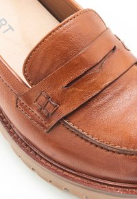 Bruine leren instapper met een gestructureerde afwerking, een decoratieve band en een stevige rubberen zool met zichtbare stiksels langs de rand.
