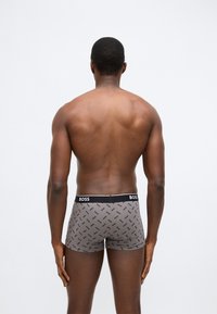 Boxerky ze šedé látky s černým pasem s logem "BOSS" a opakujícím se geometrickým vzorem ve tmavě modré barvě.